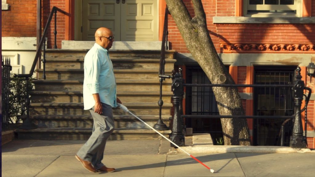 Man is walking with WeWALK down the street