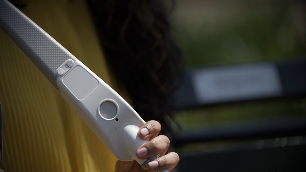 A woman holding WeWALK and showing WeWALK's front face
