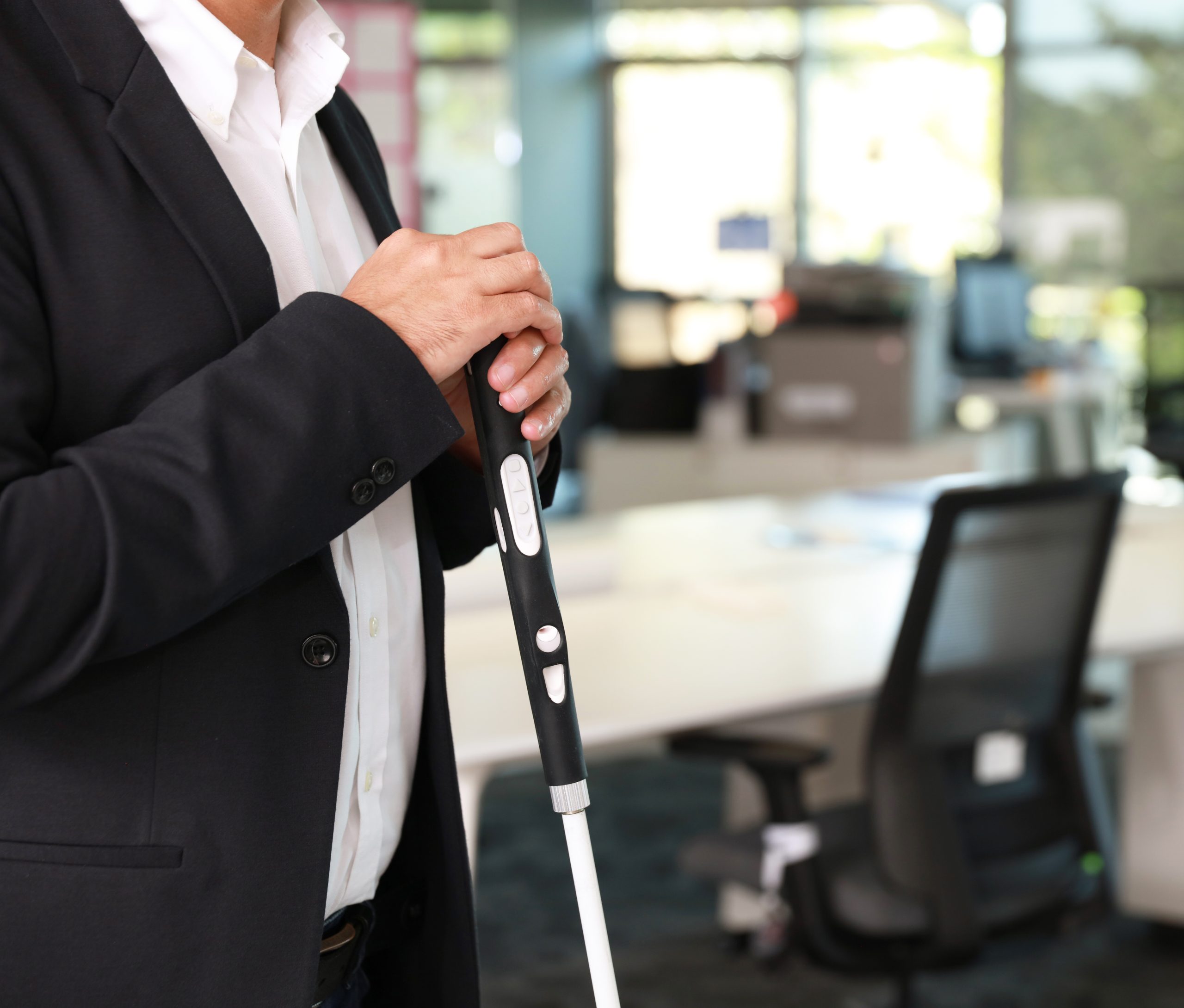 A person who is working holding on to the new smart cane 2 in a workplace